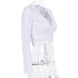 Détail d'un crop top blanc à manches longues avec sangles croisées et décolleté en V profond