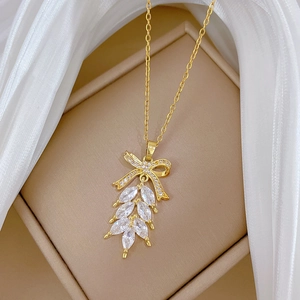 Elegante goldene Halskette mit Schleife und Kristallanhänger auf weichem Seidenstoff