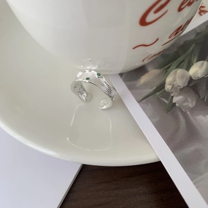Detailed shot of irregular S925 silver ring featuring green gems on a ceramic edge