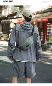Outdoor street view of a green casual crossbody chest bag with adjustable black strap