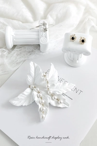 White resin jewelry display stands in leaf and Roman column shapes for rings and earrings