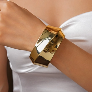 Close-up of golden geometric metal cuff bracelet with a polished mirror finish on wrist