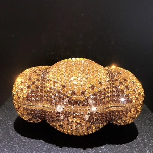 Dettaglio macro della borsa a forma di zucca con strass dorati e ambra lucidi