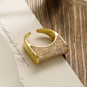 Gold plated wide band ring with pavé cubic zirconia on open vintage book background