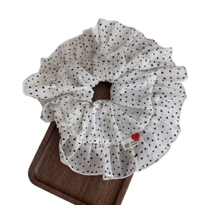 Polka dot ruffled scrunchie with handmade heart label on a wooden display tray