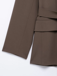 Detail of brown blazer cuff and waist tie design showing fabric texture on white background