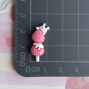 Detailed size view of strawberry and rabbit resin charm on measuring mat for DIY crafts
