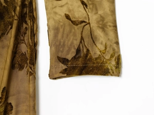 Détail de la manche d'une robe en velours marron doré avec texture florale