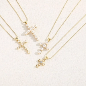 Detailed view of four elegant gold cross necklaces with pearls and sparkling zircon accents