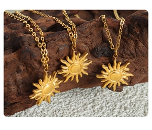 Three gold sunburst pendant necklaces displayed on dark wood and stone texture surface