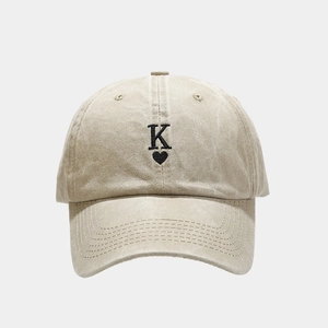 Close-up of khaki washed cotton baseball cap featuring embroidered K letter and heart