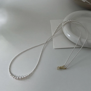 Close-up of elegant gradient pearl necklace with a refined gold clasp on white background