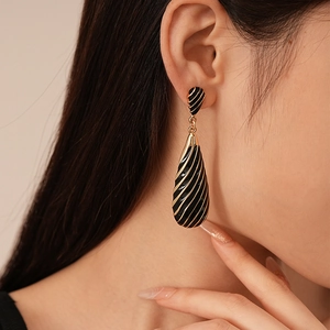 Detail of vintage zebra stripe teardrop earring with black enamel and gold spiral finish