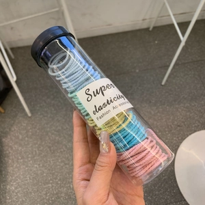 Set of multi-colored high-elasticity fabric hair ties in a portable plastic tube