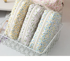 Detail of floral quilted pencil cases with metal zippers in a white metal wire basket