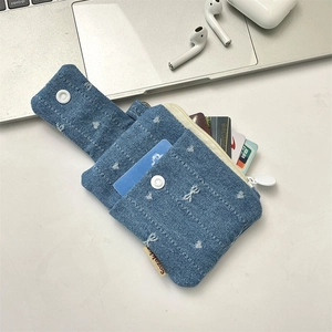 Detail of denim card holder with bow embroidery and compartments for cards
