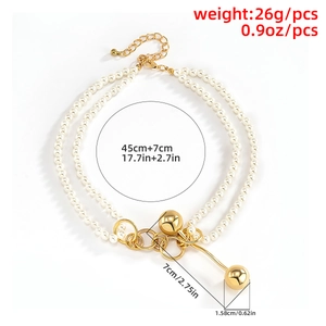 Detailed view of layered faux pearl and gold chain necklace with dual sphere pendants