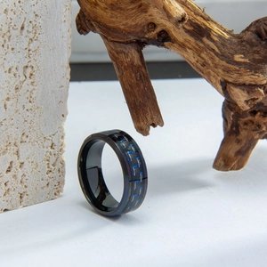 Anello da uomo in acciaio al titanio nero con inserto in fibra di carbonio blu su roccia
