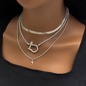 Detailed close-up of triple-layered silver chain necklace set with horseshoe lock and lightning bolt
