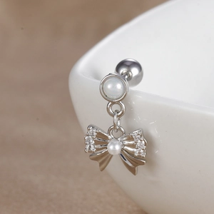 Vue macro de piercing d'hélix papillon argenté avec zircons et détail de perle sur céramique