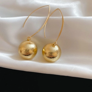 Detailed macro view of gold-finished metallic brushed texture round dangle earrings