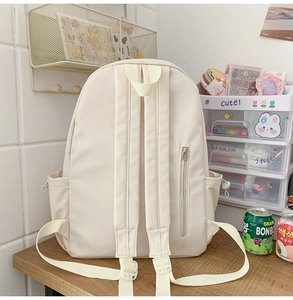 Back view of minimalist cream backpack showing padded straps and hidden zipper pocket