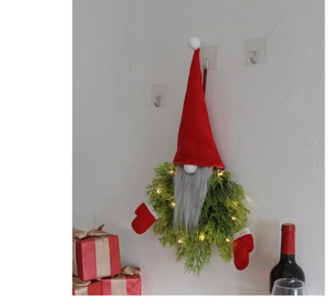 Detail of LED Christmas gnome wreath with red plush hat and glowing green pine needles
