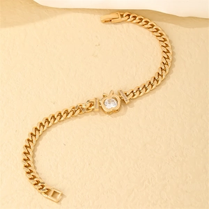 Detail of gold Cuban link bracelet featuring a crystal apple pendant with pavé accents