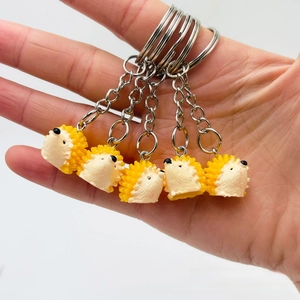 Macro shot of five yellow resin hedgehog keychains with silver rings held in hand