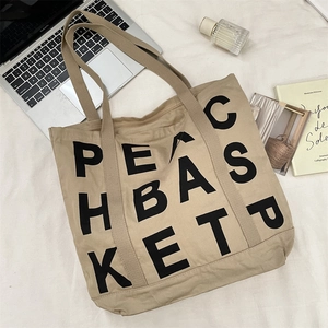 Close-up of khaki canvas tote bag featuring PEACE BASKET print and spacious interior