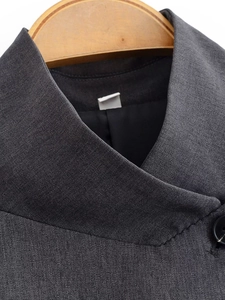 Détails de la veste de costume gris foncé montrant le col montant et la texture du tissu