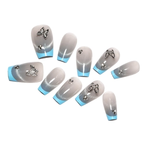 Faux ongles French bleus avec papillons argentés, effet œil de chat et strass brillants