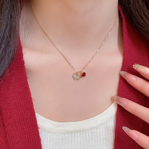 Détail d'un collier minimaliste avec chiot doré et cœur rouge sur un mannequin