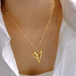 Golden heart pendant necklace with beaded chain on white shirt for elegant daily wear
