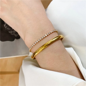 Close-up of 18K gold plated bangle and diamond-set tennis chain on a wrist