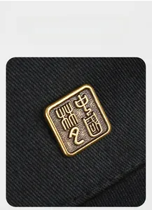 Macro shot of a bronze gold metal logo with Chinese relief on black twill baseball cap