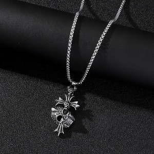 Vue macro d'un pendentif tête de mort et croix sur une chaîne en acier inoxydable
