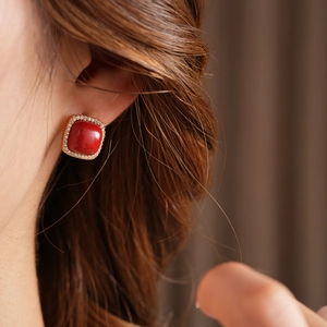 Detail of square red zircon stud earrings with gold plating worn by a model