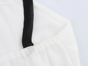 Détail du tissu blanc texturé avec un élégant dos nu noir et des plis délicats sur la robe
