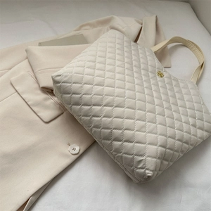 Sac fourre-tout beige matelassé avec logo doré sur un blazer chic et élégant