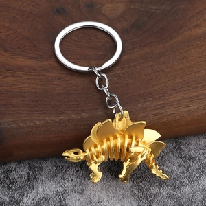 Detaillierte Nahaufnahme eines goldenen Stegosaurus-Skelett Schlüsselanhängers aus Metall