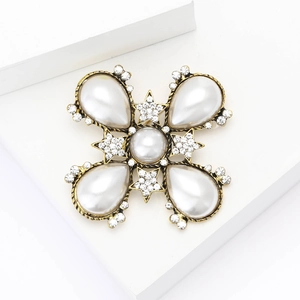 Detailed close-up of Baroque pearl brooch with gold finish and rhinestone star accents