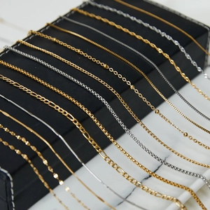 Multiple gold and silver titanium steel necklaces on a black leather display box