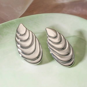 Detail of silver drop earrings with layered horizontal pleat texture on green ceramic tray