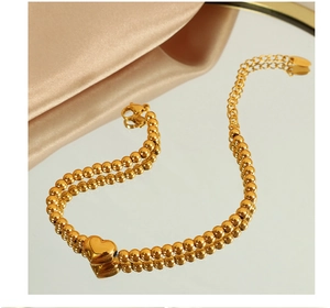 Gros plan d'une chaîne à billes double couche plaquée or 18k avec pendentif cœur