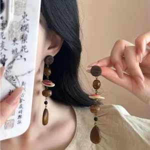 Gros plan de boucles d'oreilles vintage en nacre avec pompons et perles de bois bohème