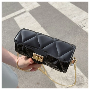 Close-up of black quilted jelly bag with gold chain strap and pearl detail in natural light