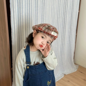 Detail of red and green plaid beret for kids featuring a white New Changes woven label