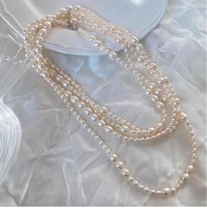 Detailed view of layered natural freshwater pearl necklaces on white silk fabric