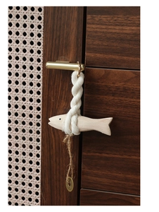 Close-up of hand-carved wooden fish with woven cotton rope and vintage gold coin detail